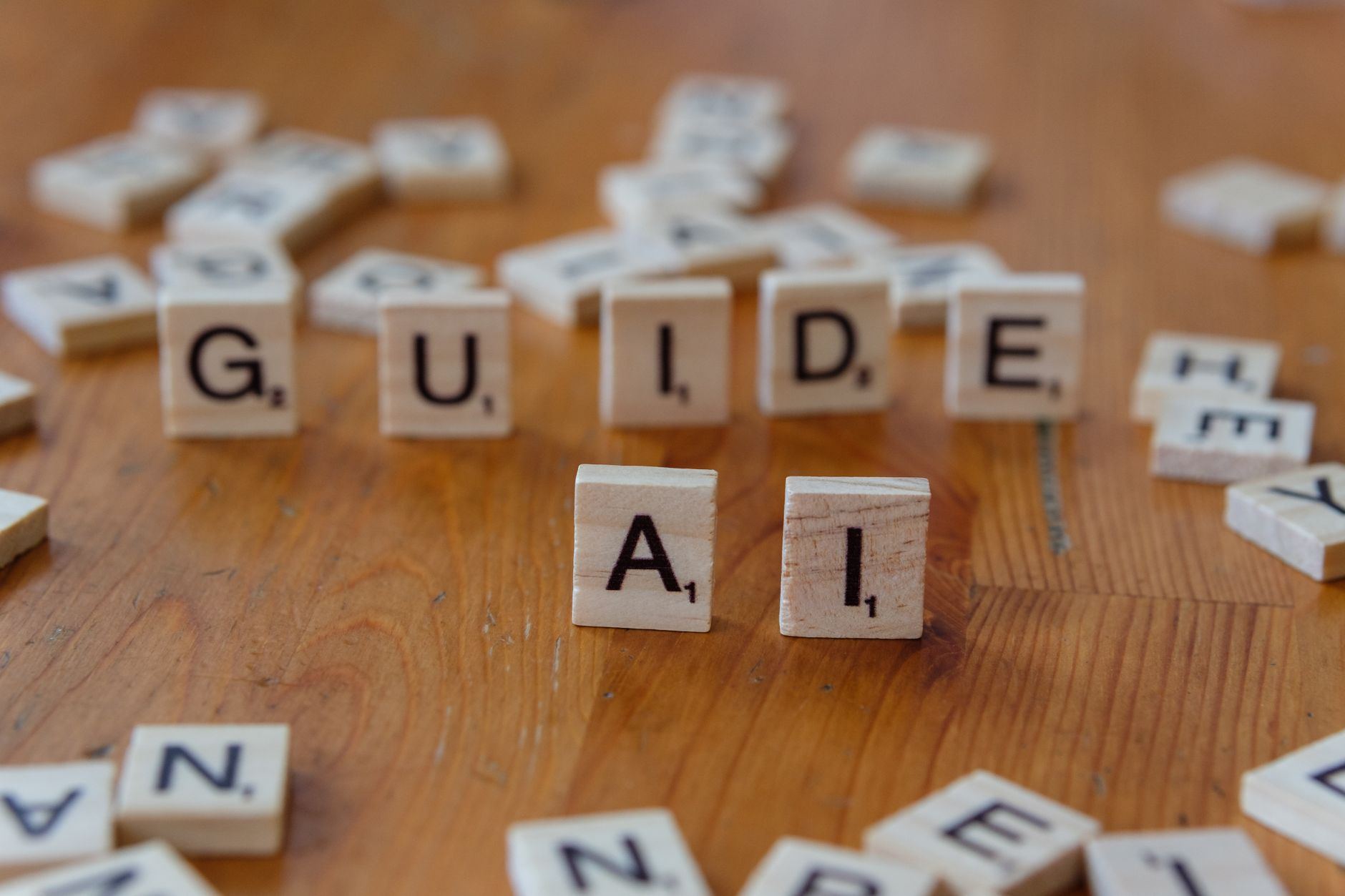Scrabble letters spelling 'GUIDE' and 'AI' on a wooden surface