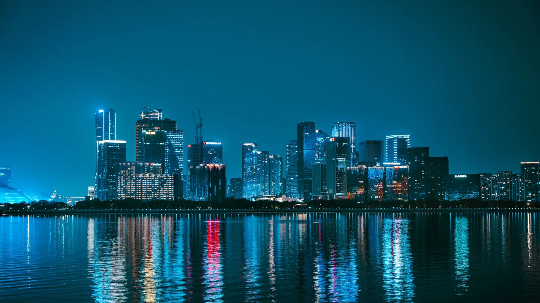 Explore the mesmerizing night skyline of Hangzhou, China, with vibrant reflections on the Qiantang River.