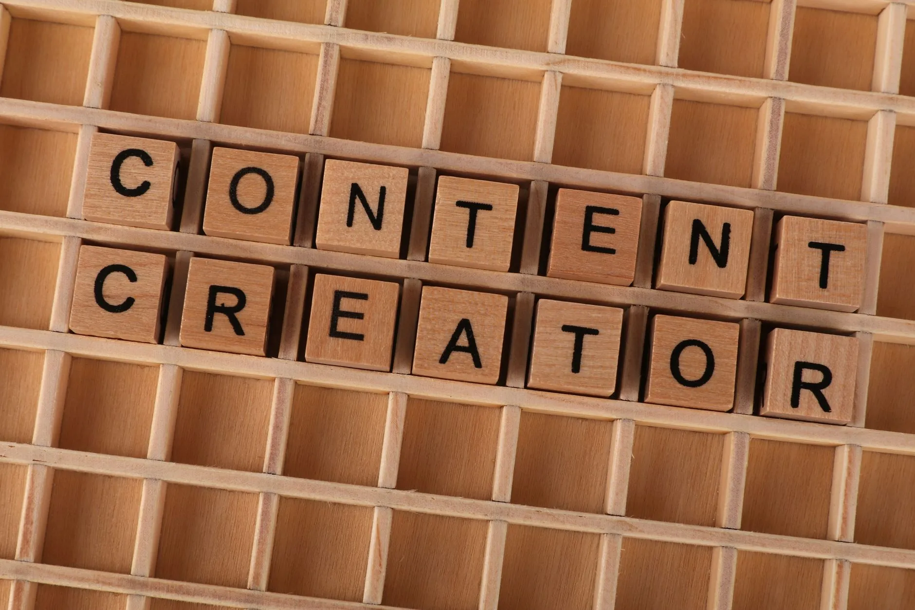 Wooden block letters spelling 'Content Creator' on a grid background. Ideal for digital marketing themes.