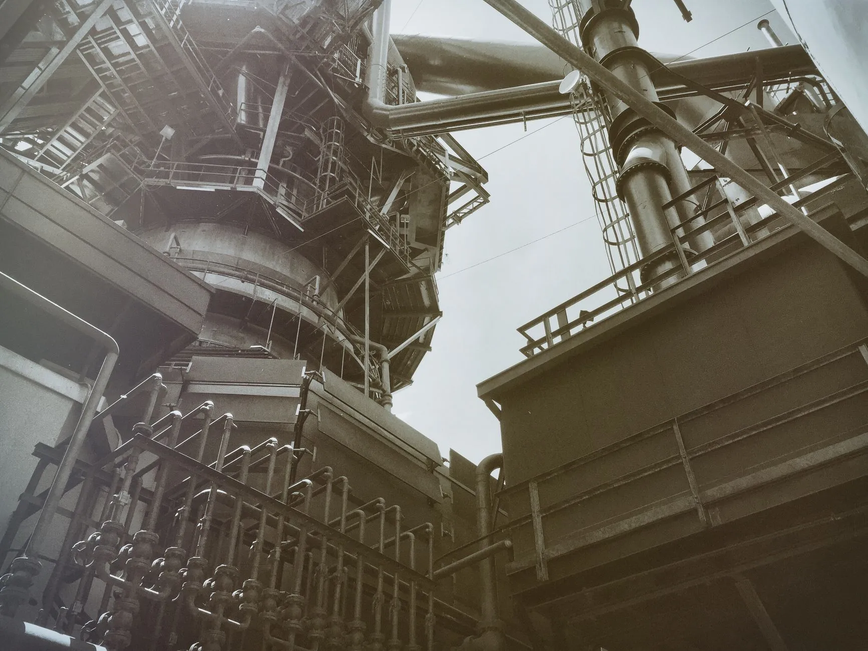 Low angle view of industrial steel structures and pipes, showcasing modern engineering.