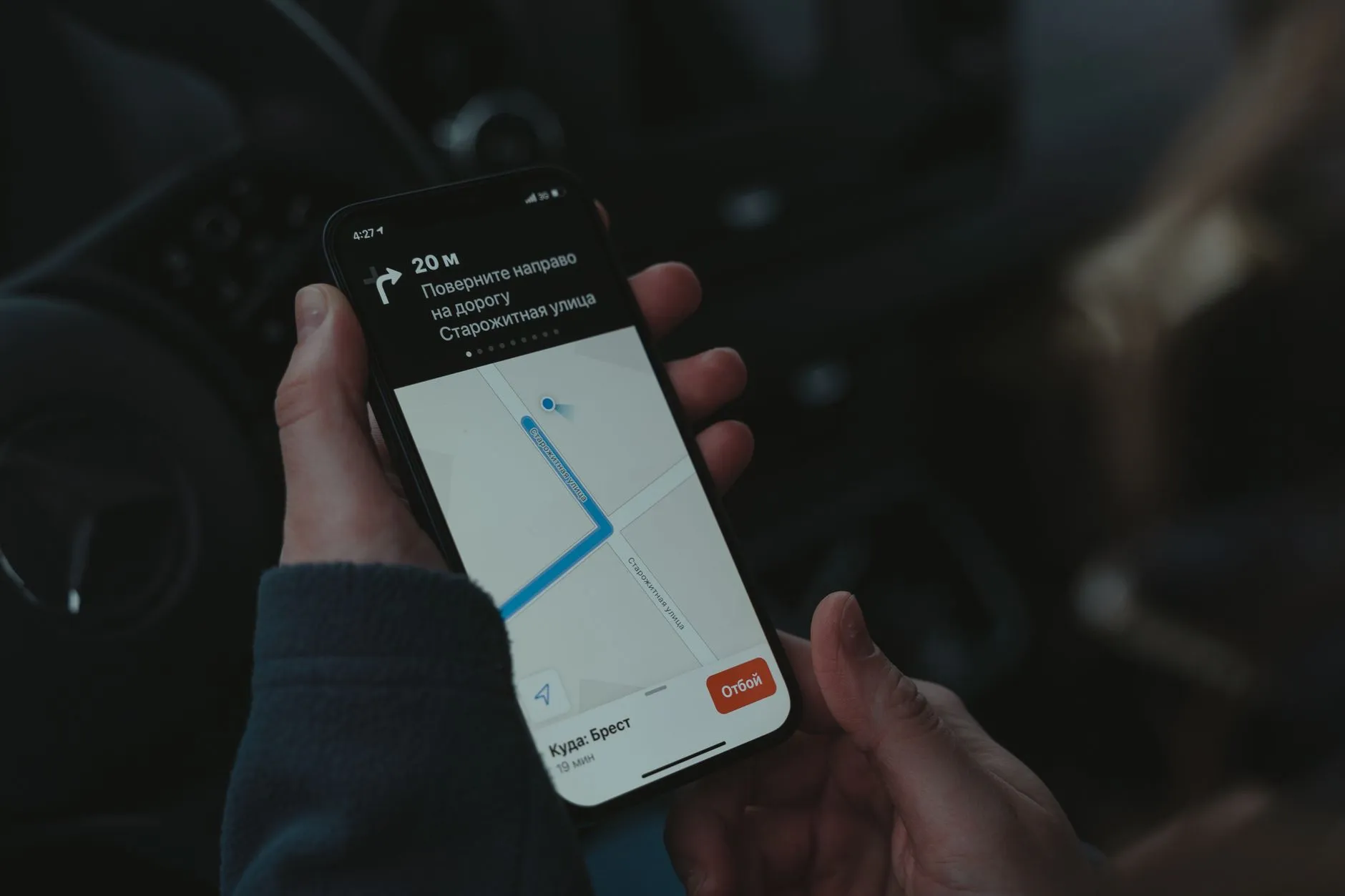 Close-up of a smartphone displaying a navigation app in a car, highlighting modern technology use while driving.