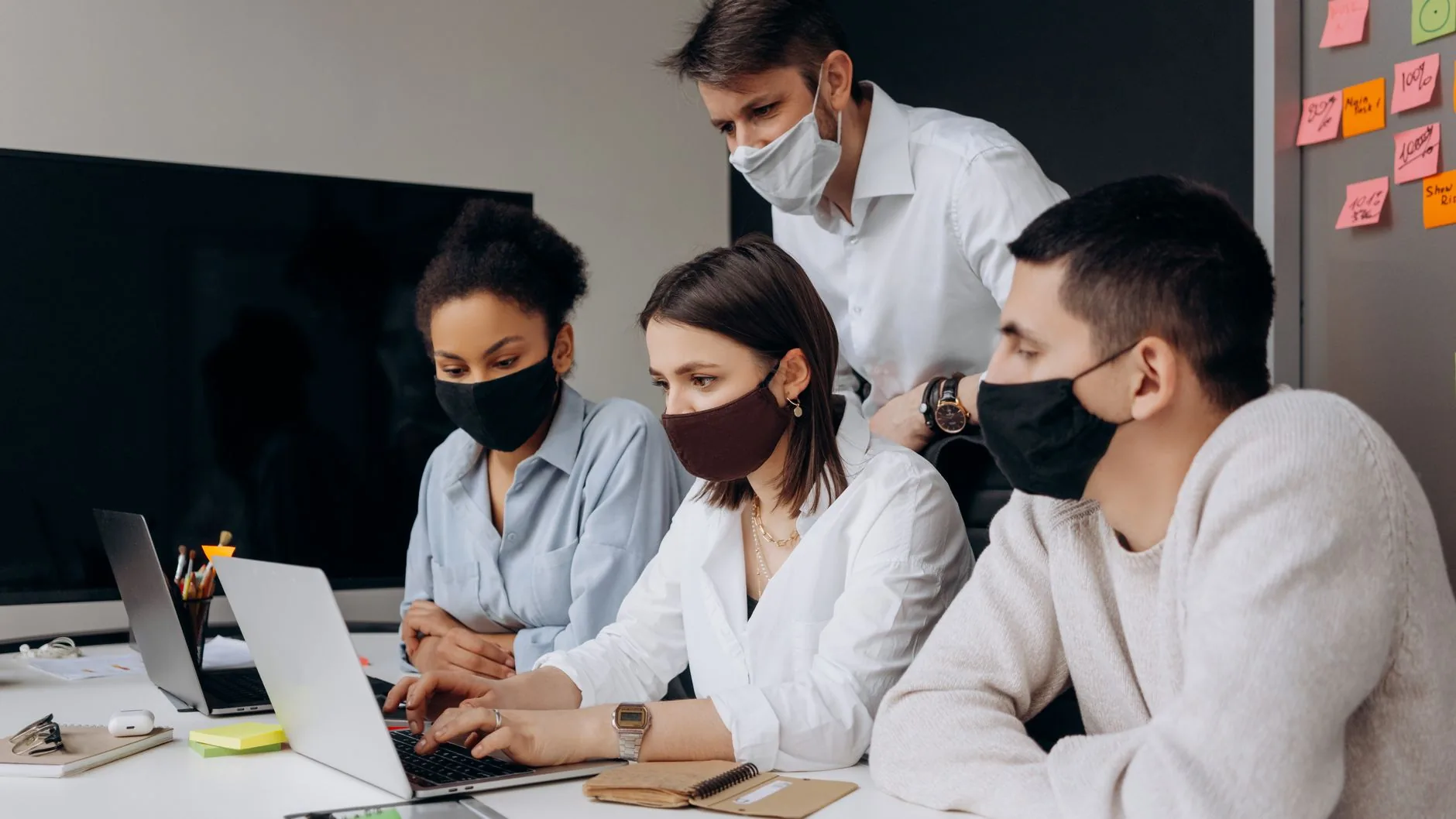 A diverse team working together in an office, showcasing safety measures with face masks.