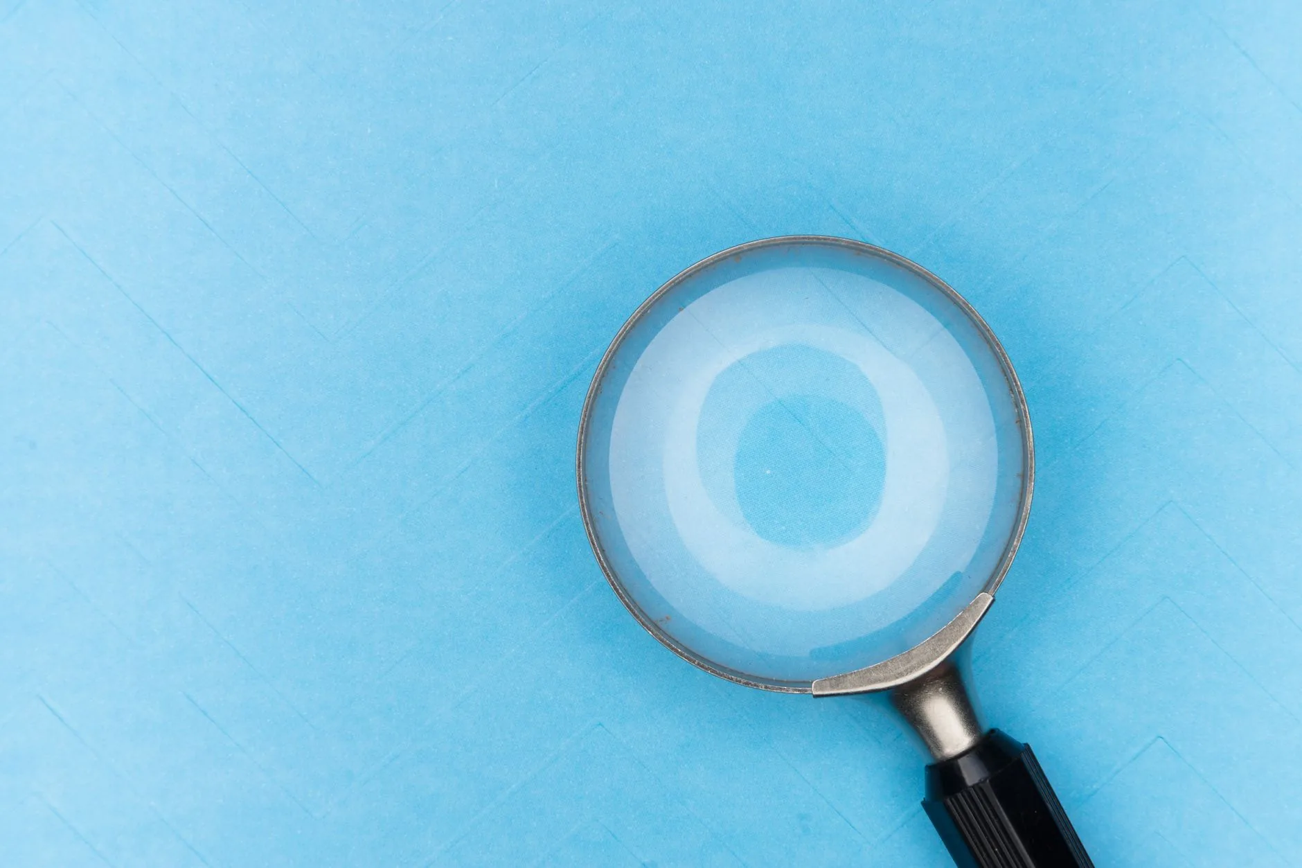 Close-up of a magnifying glass on a blue background, focusing on detail and clarity.
