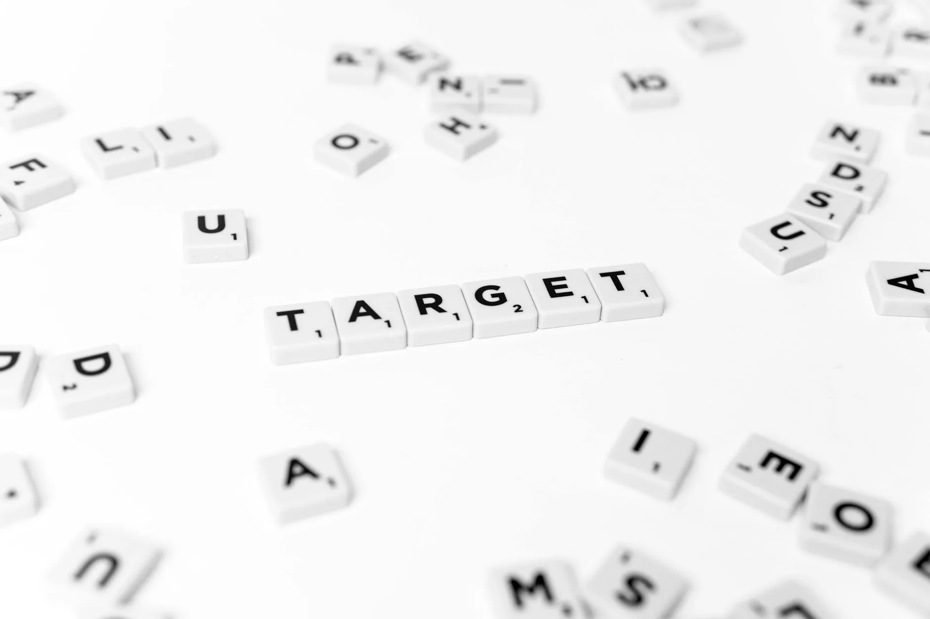 Close-up of "TARGET" spelled with Scrabble tiles on a white background. Conceptual and selective focus.