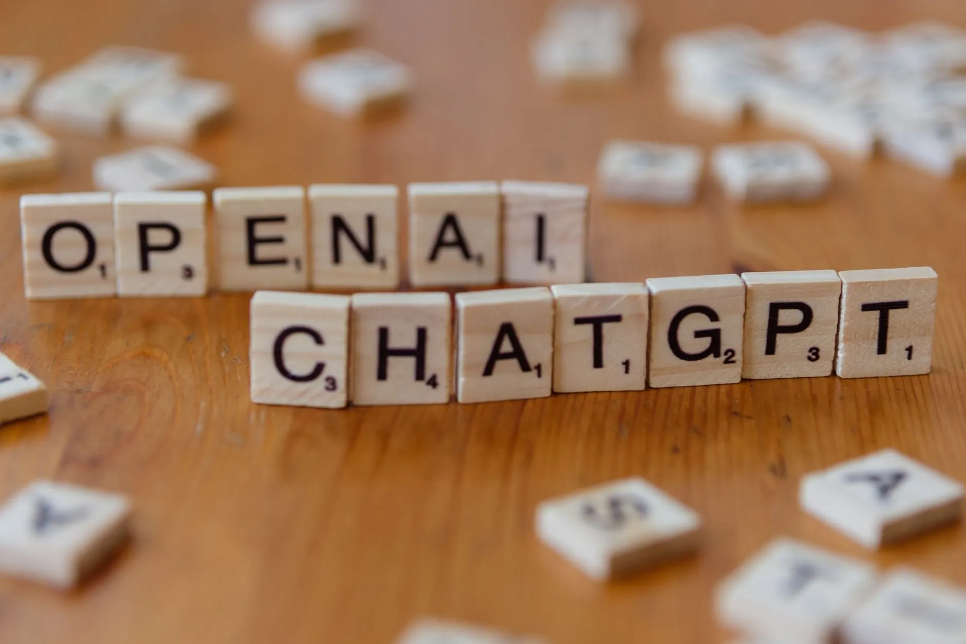 Wooden letter tiles spelling 'OPENAI CHATGPT' on a wooden surface